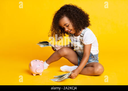 Little afro girl playing with money banknotes Stock Photo