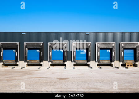 Row of loading docks with shutter doors at an industrial warehouse. Stock Photo