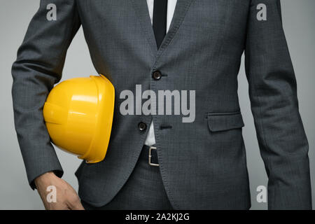 safety at work or construction business concept - businessman holding yellow helmet underarm Stock Photo