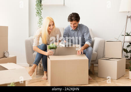 Young man and woman packing things in moving boxes indoor Stock Photo
