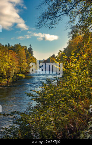 Fall Leaves on Trees on the Banks of the River Teith in Scotland with Doune Castle and Stone Bridge in the Background Stock Photo