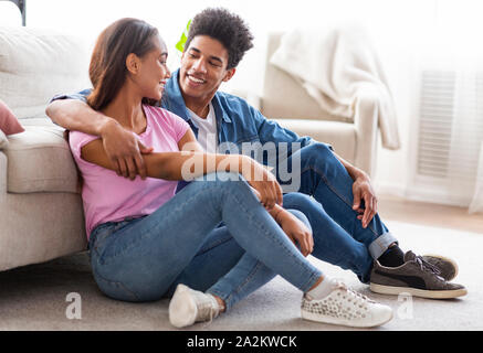 Cheerful african couple sitting on floor and talking Stock Photo