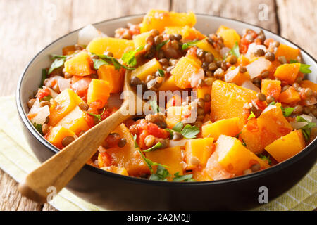 Spicy vegetable stew of pumpkins, tomatoes, lentils, onions and carrots close-up in a bowl on the table. horizontal Stock Photo