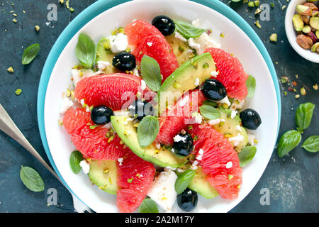 Avocado salad with grapefruits, feta cheese, black olives and pistachio. Top view with copy space. Healthy food. Stock Photo