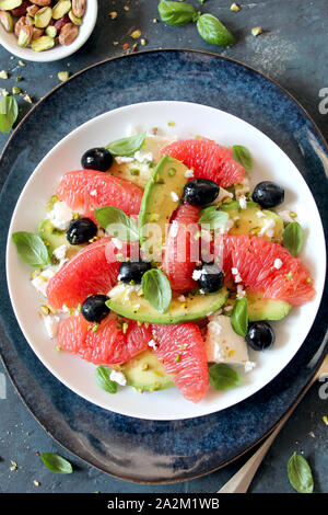 Avocado salad with grapefruits, feta cheese, black olives and pistachio. Top view with copy space. Healthy food. Stock Photo
