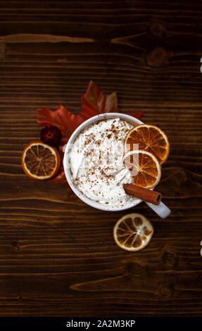 Vertical top view of warm cup of coffee with cinnamon and dried oranges on wooden background. Stock Photo