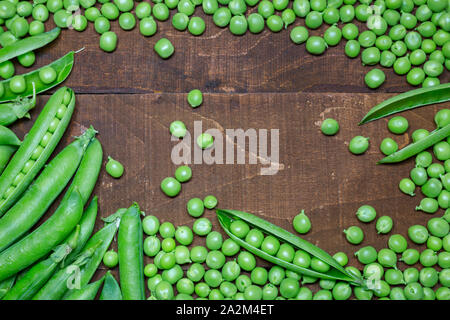 Fresh green peas and pods on rustic wooden background, top view with copy space. Concept of healthy eating, fresh vegetables. Stock Photo