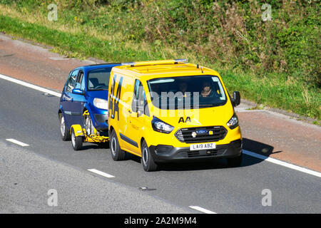 AA Van yellow 24hr recovery truck, Ford Transit Custom 340 Base carrying broken down vehicle. Side view of rescue breakdown recovery vehicle transporting blue small family car along M6, Lancaster, UK; Vehicular traffic, transport, modern, north-bound on the 3 lane highway. Stock Photo