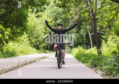 Young male cyclist celebrating victory with hands up Stock Photo
