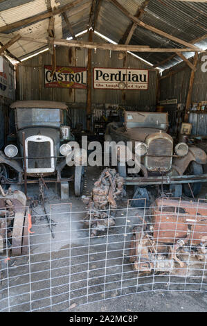 Old Tailem Town Pioneer Village, Australia’s largest pioneer village museum.   A couple of rusty vintage cars with engines on the floor at the garage Stock Photo