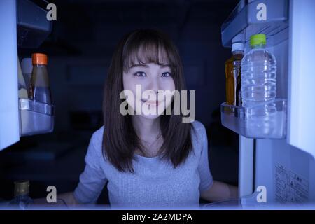 Young Japanese woman eating night snack from the fridge Stock Photo