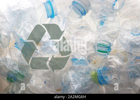 a transparent recycle symbol put on a lot of crushed plastic bottles Stock Photo
