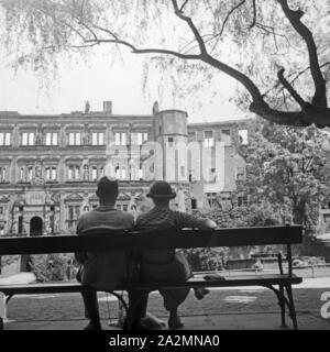 Ein Paar sitzt auf einer Bank mit Blick auf das Schloss in Heidelberg, Deutschland 1930er Jahre. A couple sitting on a bench with view to Heidelberg castle, Germany 1930s.