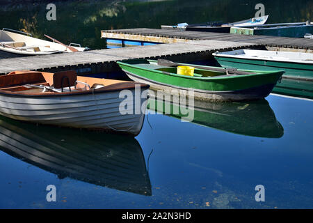 Some angler boats of different colors in a lake, reflecting in the water. Stock Photo