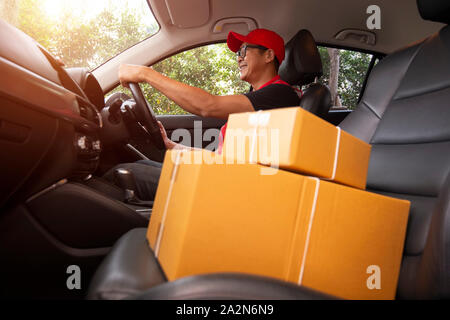 The delivery driver Man driving van with parcels box on seat outside the warehouse, cargo truck delivering a package for the customer. Stock Photo