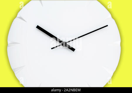 White wall clock with black clock hands hanging on the yellow wall. Minimalist flat lay image. Stock Photo