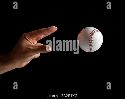 Baseball pitcher, close up of the hand ready to pitch on black background. Stock Photo
