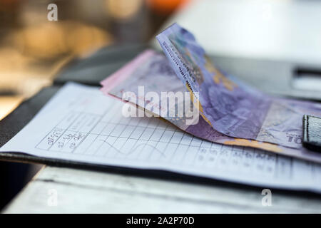 Restaurant bill with money on payment tray on the table, money is rupiah Stock Photo