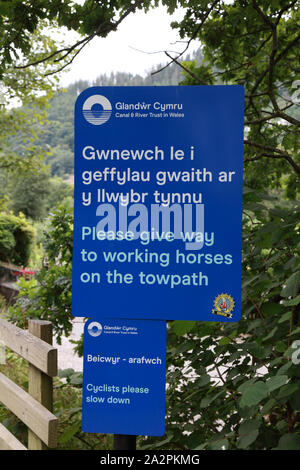 A sign in Welsh and English by the Canal & River Trust in Wales on the towpath on the Llangollen canal in Llangollen Stock Photo