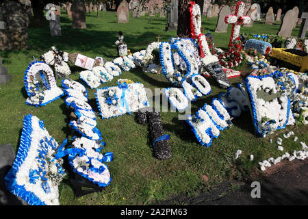 A much decorated grave including floral signs for Husband, Dad, Brother and Grandad (on the left) Stock Photo