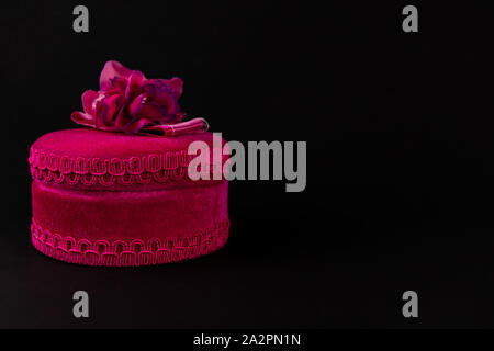 Pink round gift box with ribbon isolated on a dark background Stock Photo