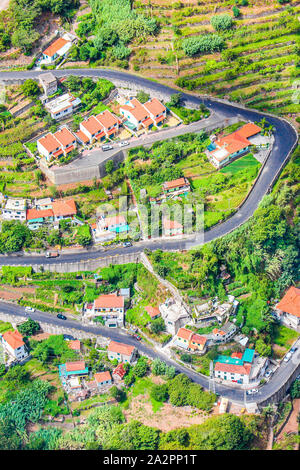 Aerial view of a village Curral das Freiras, Madeira Island, Portugal. Countryside houses, green terraced fields, and scenic serpentine road photographed from above. Aerial landscape. Travel spot.