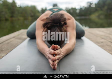 Woman in yoga childs pose with hands clasped, outdoors.