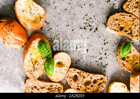 Oven baked bruschetta with basil and olive oil in the oven. Traditional italian appetizer. Top view Stock Photo