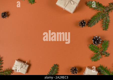 Christmas or winter composition. Frame made of fir tree branches, pine and handmade gift boxes on pastel orange background. Christmas, winter, new yea Stock Photo