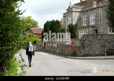 Rear view of a woman walker walking to Virginia Woolf home Monks House through the village of Rodmell East Sussex England UK  KATHY DEWITT Stock Photo