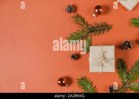 Christmas or winter composition. Frame made of fir tree branches, pine and handmade gift boxes on pastel orange background. Christmas, winter, new yea Stock Photo