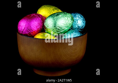 Bowl of foil wrapped chocolate Easter eggs isolated on black Stock Photo