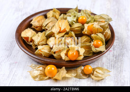 Physalis on clay dish. Ripe berries of autumn physalis fruit Stock Photo