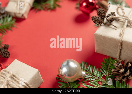 Christmas handmade gift boxes decorated with craft paper and branch, pine cone, cinnamon on red background. Christmas, winter, new year concept. Flat Stock Photo