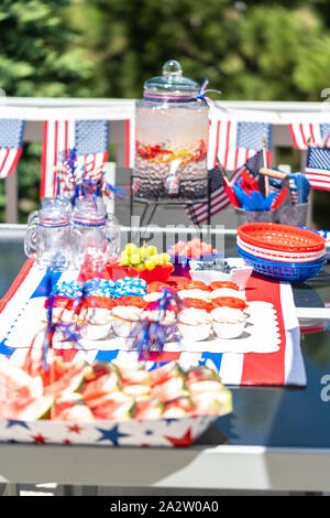 Table with food and drinks set for celebrating July 4th on the back patio. Stock Photo