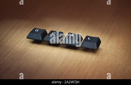 Keyboard keys placed on a wooden table forming the word GOAL. Stock Photo