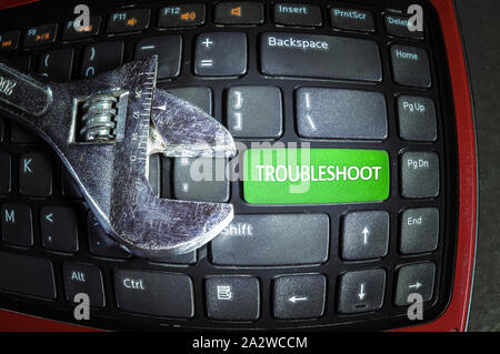 Fish eye effect. Troubleshoot green button on dirty computer keyboard with wrench tool. Stock Photo