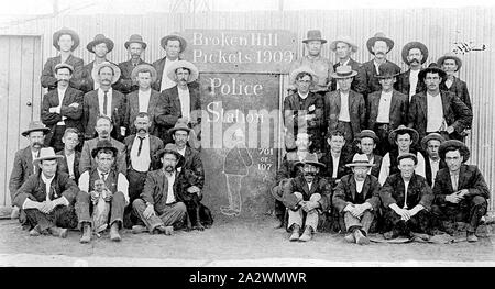 Negative - Group Portrait of Picketers at the Police Station, Broken Hill, New South Wales, 1909, Strikers (?) with signs: 'Broken Hill Pickets 1909' and'Police Station 708 or 107', the police station sign has a drawing of a fat policeman. One man holds a dog