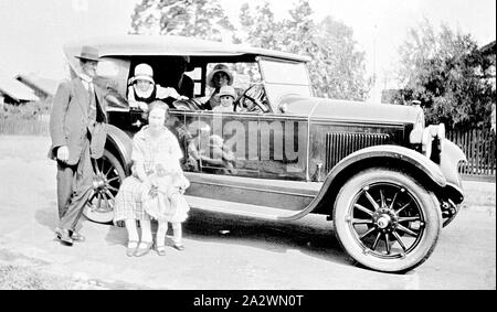 Negative - Family Outing in an Armstrong Siddeley Motor Car, Malvern East, Victoria, 1926, A family outing in an Armstrong Siddeley motor car. A woman sits on the running board with a small child. Four others look out from inside the car Stock Photo