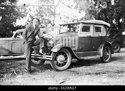 Negative - Man With Model A Ford on Main Street, Avoca, Victoria, circa 1935, A man with his foot on the front bumper of an A Model Ford parked on the median strip of the main street Stock Photo