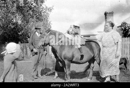 Negative - Lake Mundi, Victoria, 1924, A young girl on horseback. She is riding bareback and a woman on the right is holding onto her skirt. There is a man on the left and another woman largely obscured by the horse. A small child is on the left Stock Photo