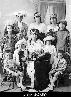 Negative - Victoria, pre 1930, A group, largely in fancy dress (the two small boys in the front are wearing street clothes). The woman in the centre is dressed as a queen with a crown, robe and sceptre Stock Photo