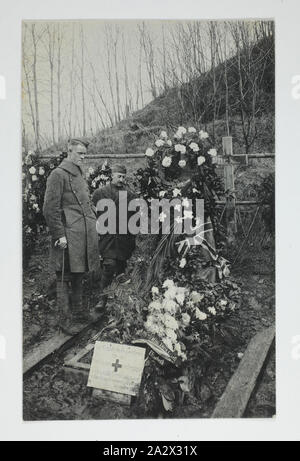 Photograph - Grave of Miss Edith Cavell, Brussels, Belgium, World War I, 1915-1918, Two men standing next to the Belgium grave of Edith Cavell, heroic British nurse who was executed for treason by the Germans on 12 October 1915, during World War I. Accounts of her death indicate that she was buried outside Saint-Gillies Prison in Belgium, where she was executed. After the war her remains were retuned to England. A remnant of the cross over her grave (likely that seen in Stock Photo