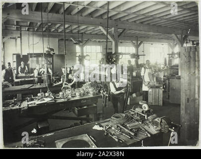 Photograph - Hecla Electrics Pty Ltd, Assembly Workers, 1920s, Photograph of male Hecla employees assembing electrical products, possibly at Hecla's Little Bourke Street premises in Melbourne. To the left of the image partially completed kettles and electric heaters are visible. At the right are pieces of ornamental metalwork including a winged sphinx and metal plaque of names. This suggests an early date for the photograph, as Hecla moved preogressively Stock Photo
