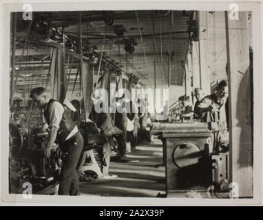 Photograph - Hecla Electrics Pty Ltd, Factory Workers, circa 1920, Black and white photograph of factory workers using industrial equipment at Hecla Electrics, possibly at the Little Bourke Street, or Little Collins Street premises in Melbourne. The style of dress suggests the photo was taken circa early 1920s. This photograph is from an album containing 255 black and white photographs depicting electrical appliances, showroom displays, factory interiors Stock Photo