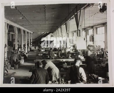 Photograph - Hecla Electrics Pty Ltd, Factory Workers, circa 1920, Black and white photograph of employees at a Hecla Electrics factory in the 1920s. The photograph may be of the Little Collins Street, or Little Bourke Street premises. The slogan By Hecla it's good - as used to comedic effect by Graham Kennedy in Hecla's pioneering TV advertising - is displayed in the workshop as well as on the packaging. This photograph is from an album containing 255 black Stock Photo
