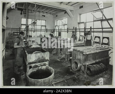 Photograph - Hecla Electrics Pty Ltd, Workers Shaping Metal Components, circa 1930, Photograph of male factory workers plating metal components of Hecla heaters, possibly in the Little Bourke Street Hecla factory, Melbourne. Facings for 'Century' model heaters are visible alongside the tubs. To the left of the image a man washes components prior to the electroplating process. The facings and other components are then slotted onto poles and suspended over the tubs for nickel Stock Photo