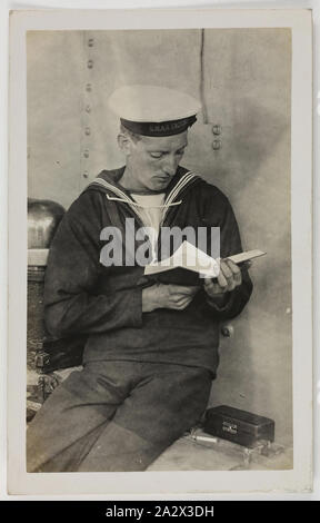Photograph - HMAS Australia, Portrait of A Seaman Reading, 1914-1918, One of 63 postcards contained in an album that was owned by Cliff Nowell. There are 25 postcards mounted inside the album and 38 postcard held loosely with in it, (loose postcards housed separately). The images depict photographs of sailors from HMAS Australia and of family and friends. It also conatins a mixture of hand-painted cards (two), original photographs Stock Photo