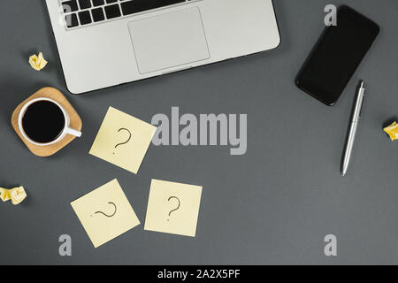 Asking, Decisions. Question mark on sticky notes, notebook, cup coffee, phone, pen on gray background. FAQ concept. Working with clients. Troubles in Stock Photo