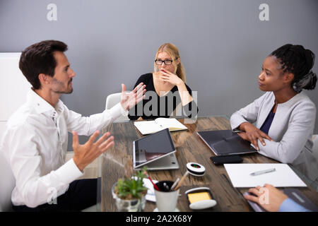 Female Colleagues Looking At Male Executive Discussing Project Plan In Meeting Room Stock Photo